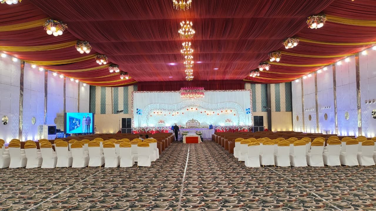 Banquet hall with stage, chandeliers and seating at The Bharat Celebrations